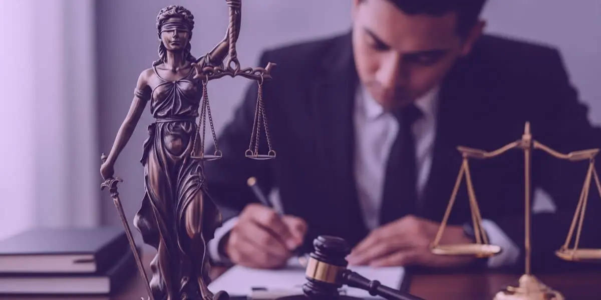 Estátua da Justiça em primeiro plano e advogado trabalhando ao fundo